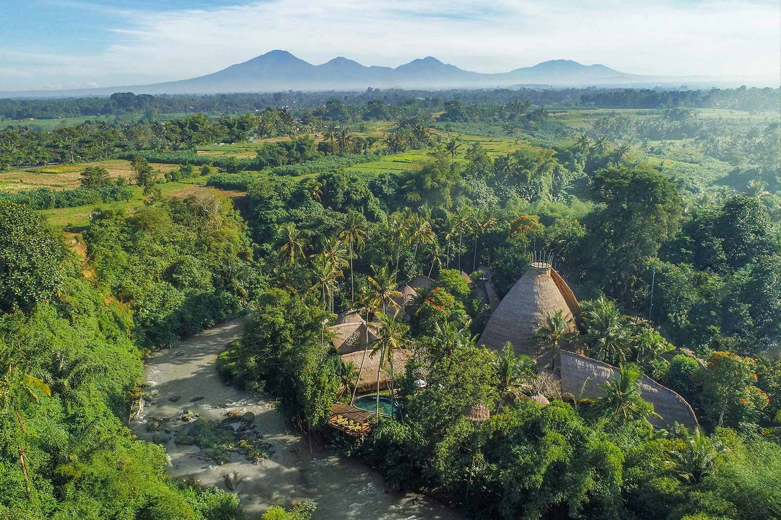 Aerial view of Fivelements Retreat on the Ayung River, Bali — thatched bamboo pavilions in the jungle